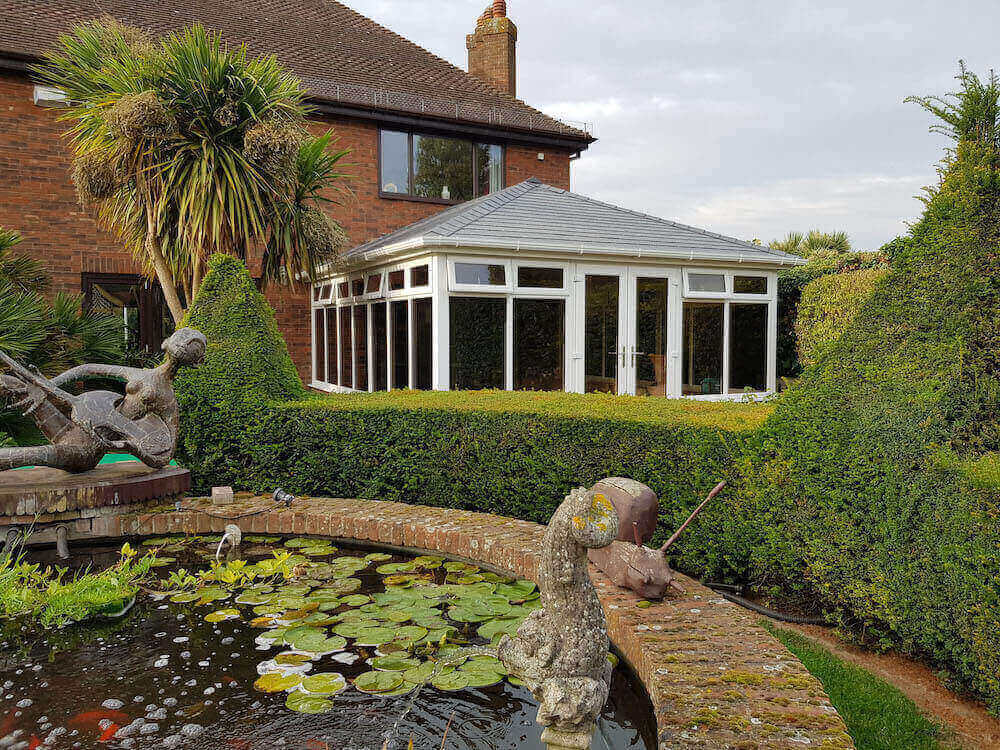 A black tiled roof on a white upvc conservatory.