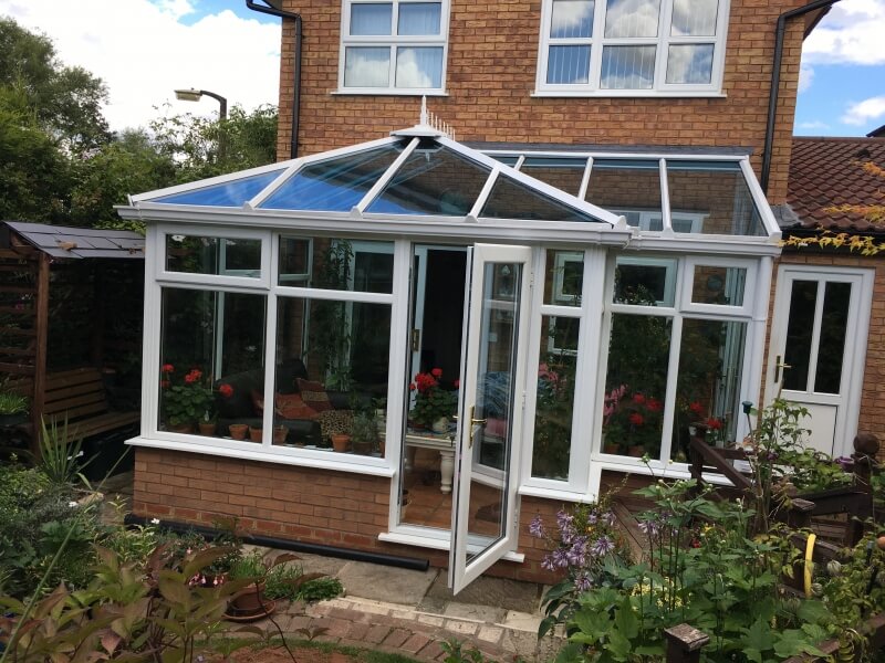 White conservatory with tinted glass roof.